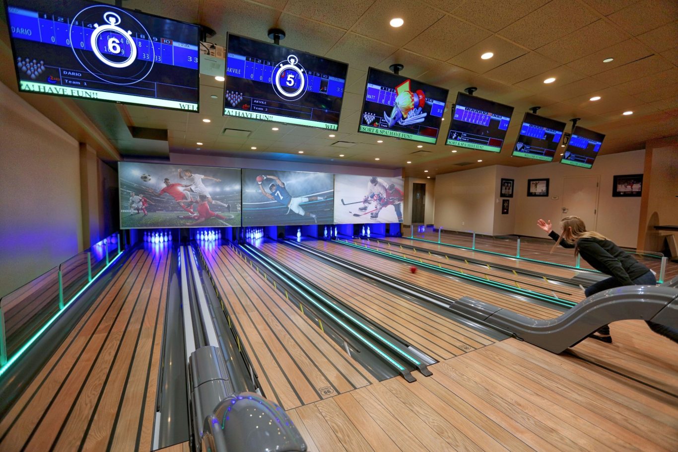 Bowling alley with multiple lanes, screens displaying graphics, and colourful LED lighting.