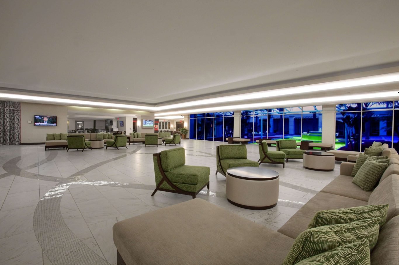 Modern lounge area with green chairs, circular tables, and large windows.