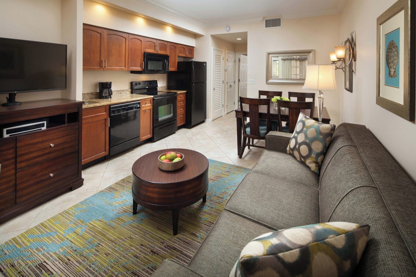 Modern kitchen and living area featuring a sofa, dining table, and wood cabinetry.
