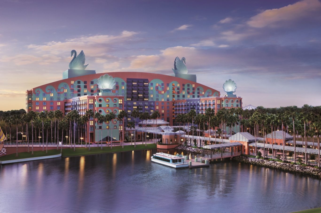 Colourful hotel with ornate sculptures, situated by a calm waterway at dusk.