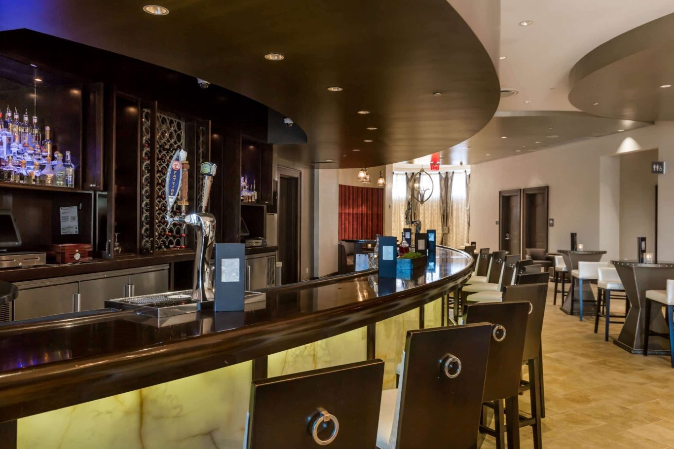 Modern bar interior with a sleek counter and elegant seating arrangements.
