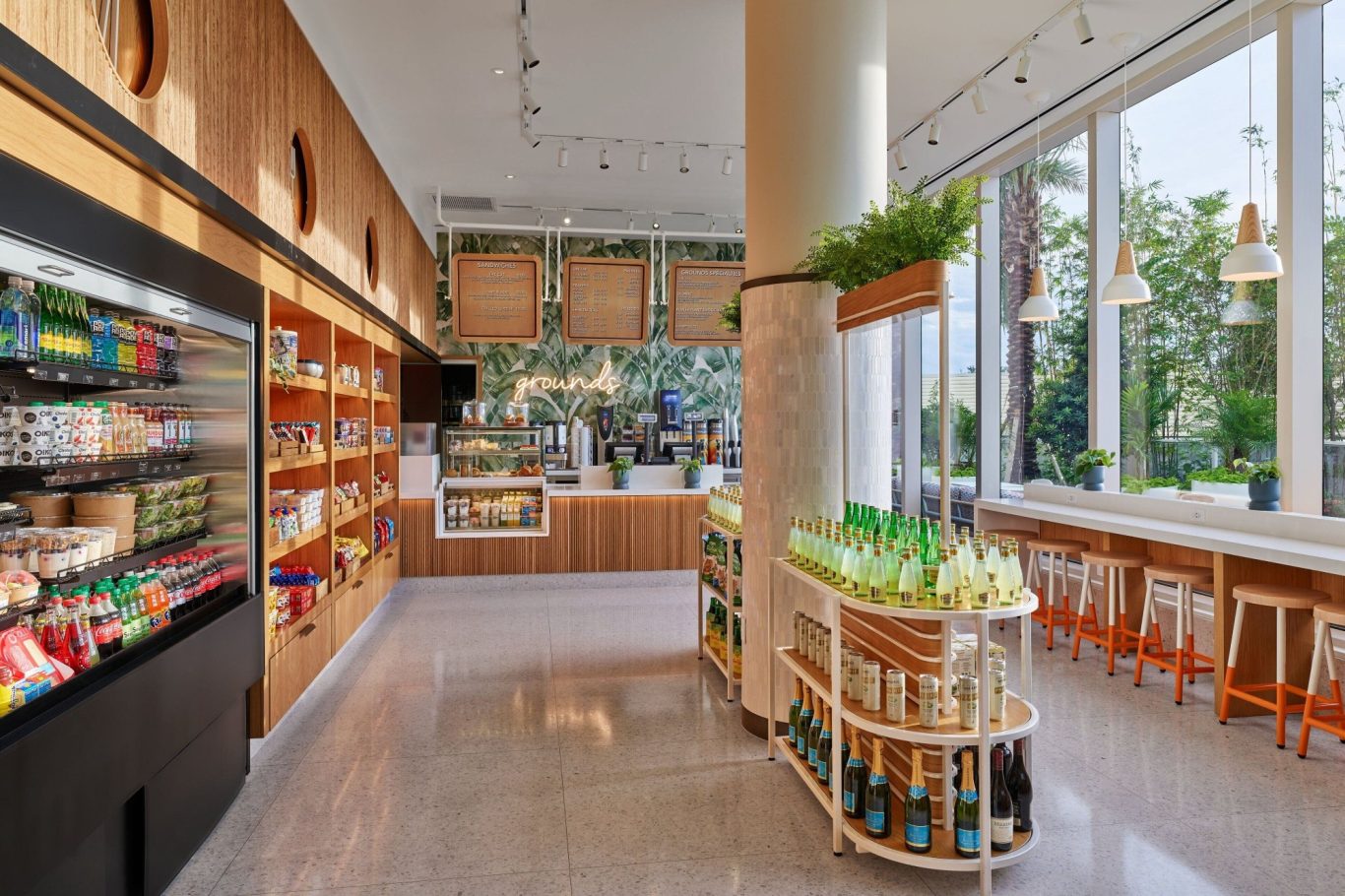 Bright, modern café interior with shelves of products and seating by large windows.