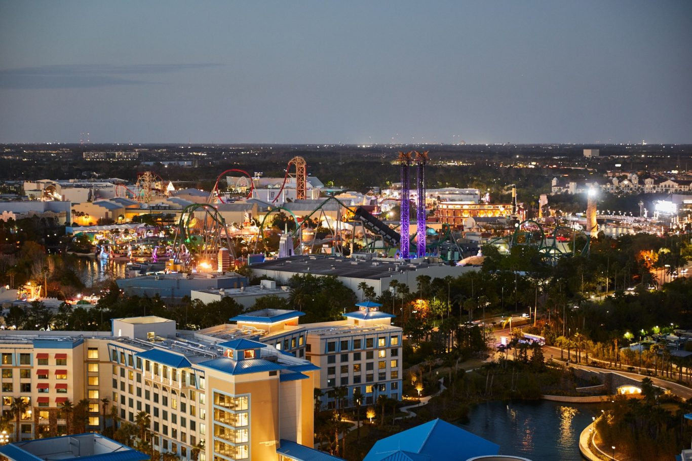 Aerial view of a vibrant amusement park lit up at night.