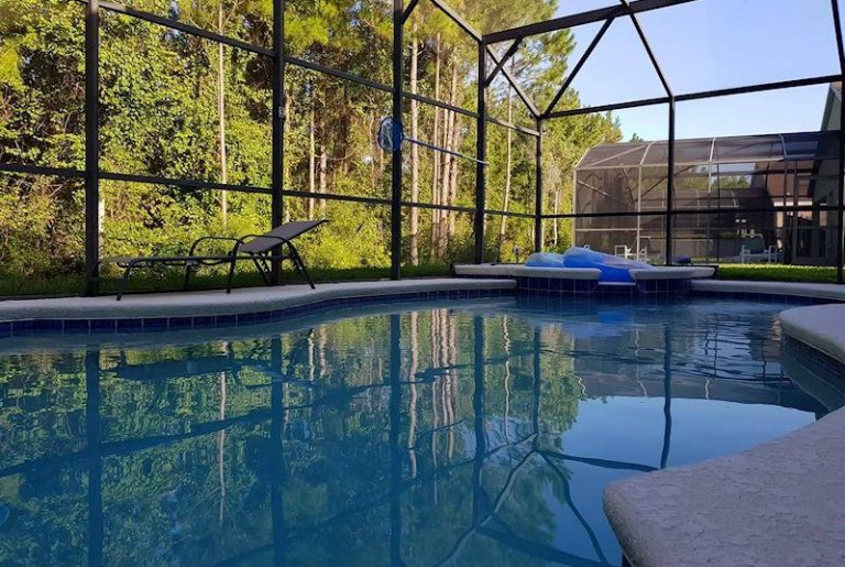 A serene pool area surrounded by trees and a protective screen enclosure.