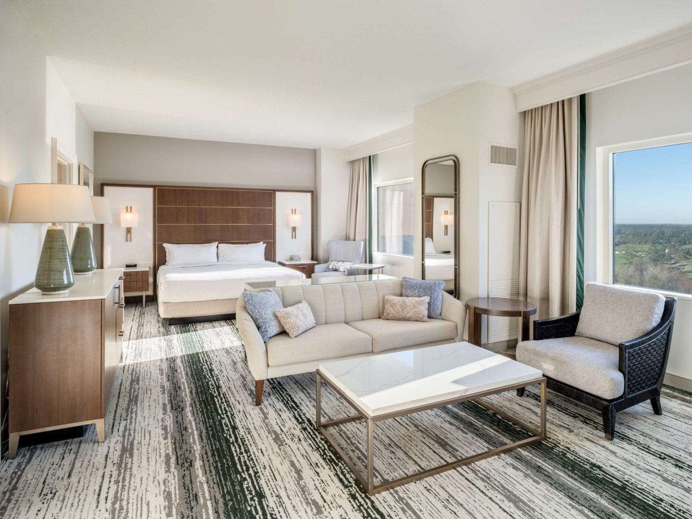 Modern hotel room featuring a bed, seating area, and large window with a view.
