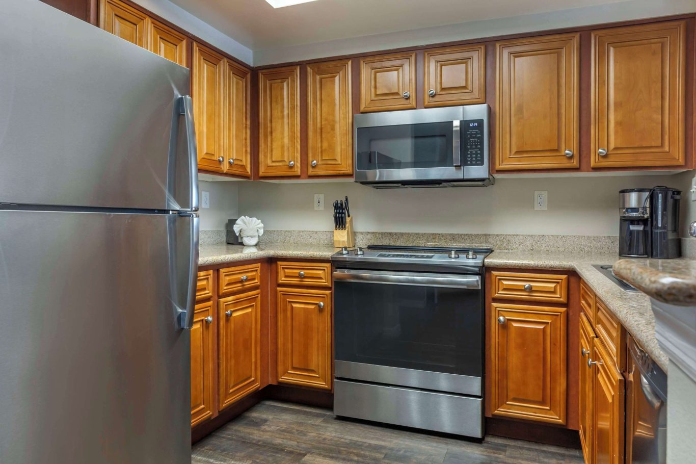 Modern kitchen with wooden cabinets, stainless steel appliances, and a neutral countertop.