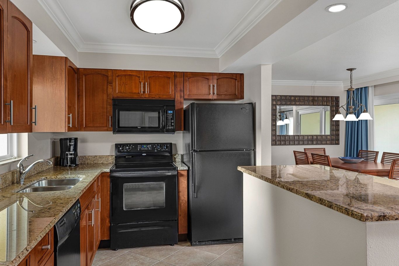 Modern kitchen featuring wooden cabinets, black appliances, and a granite countertop.
