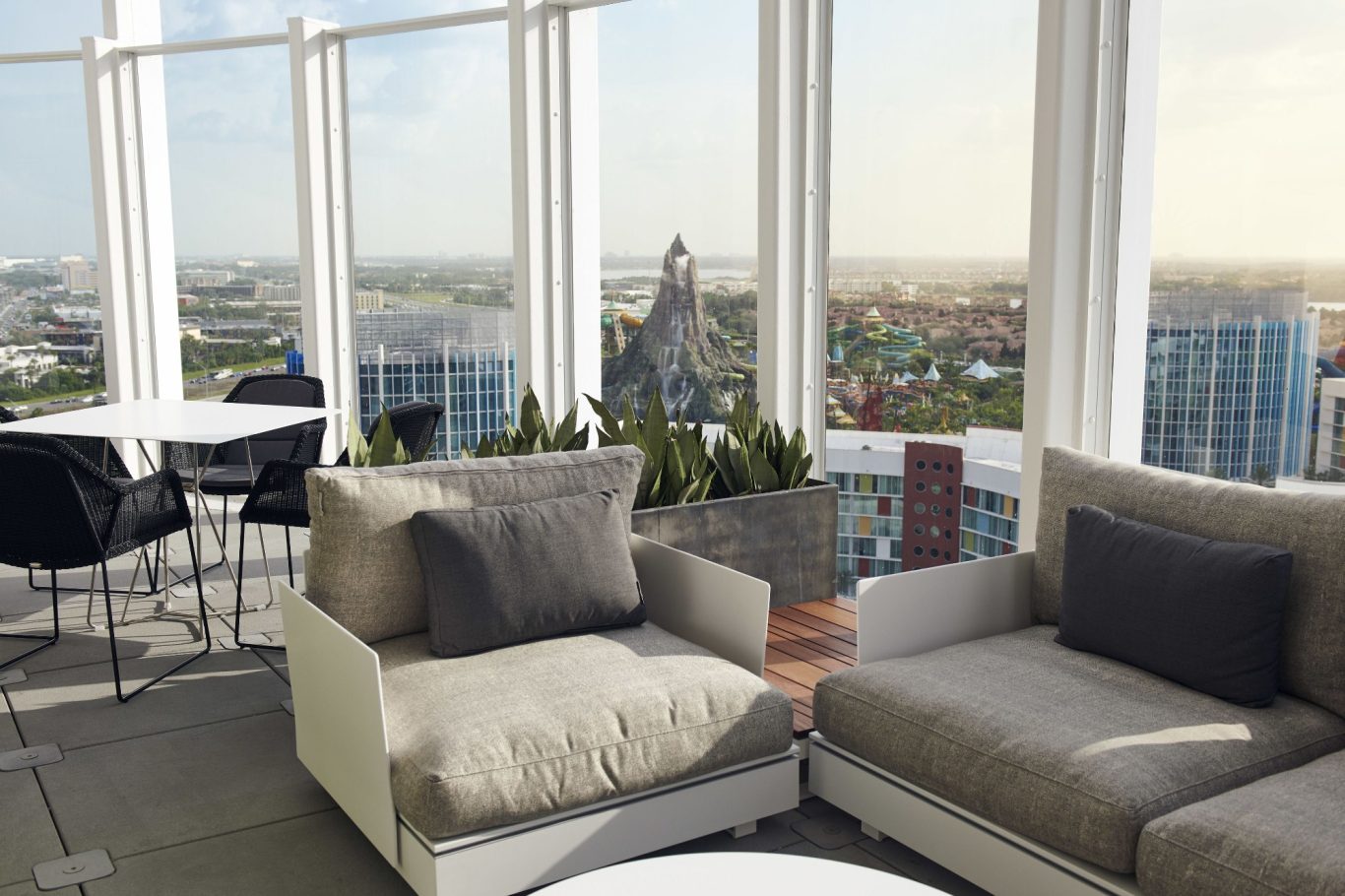 Stylish seating area with a city view, featuring modern furniture and greenery.