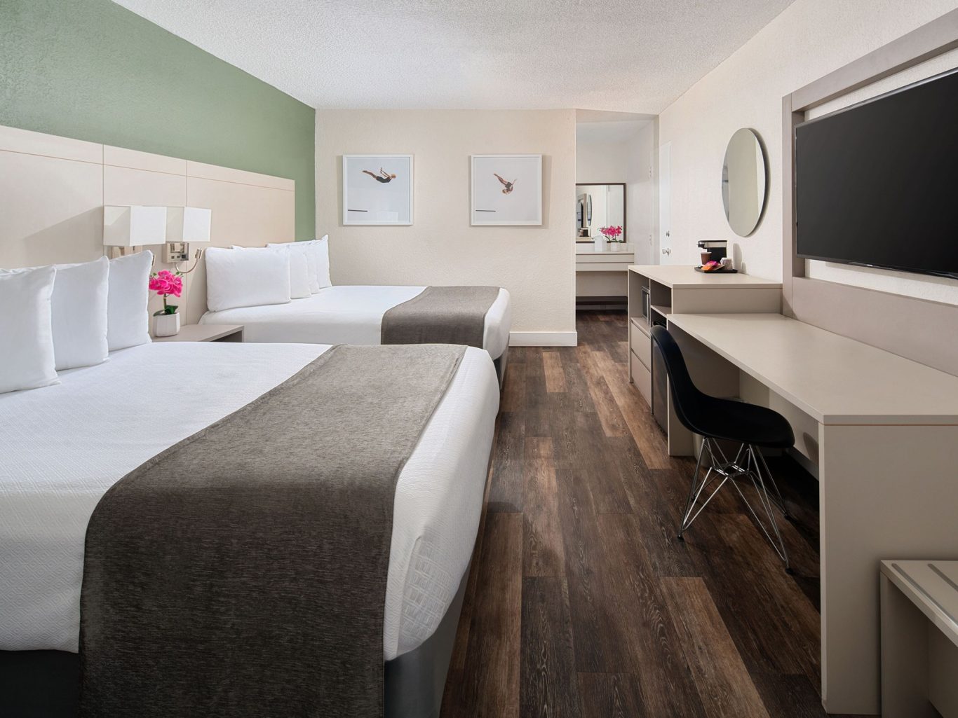 Modern hotel room with two beds, a work desk, and stylish decor in neutral tones.