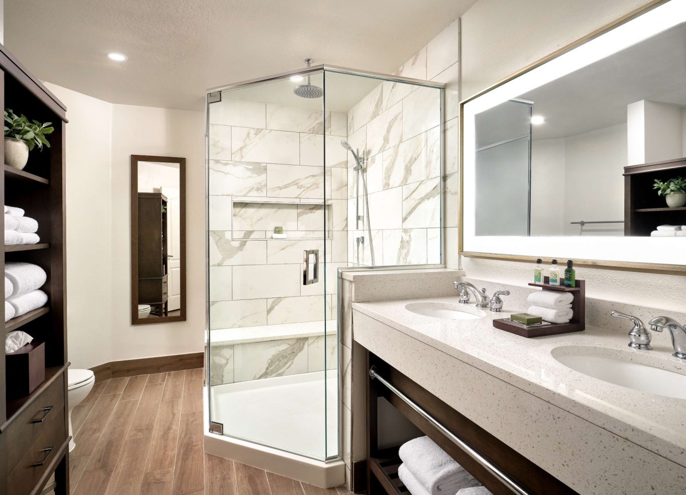 Modern bathroom featuring a glass shower, large mirror, and neatly arranged towels.
