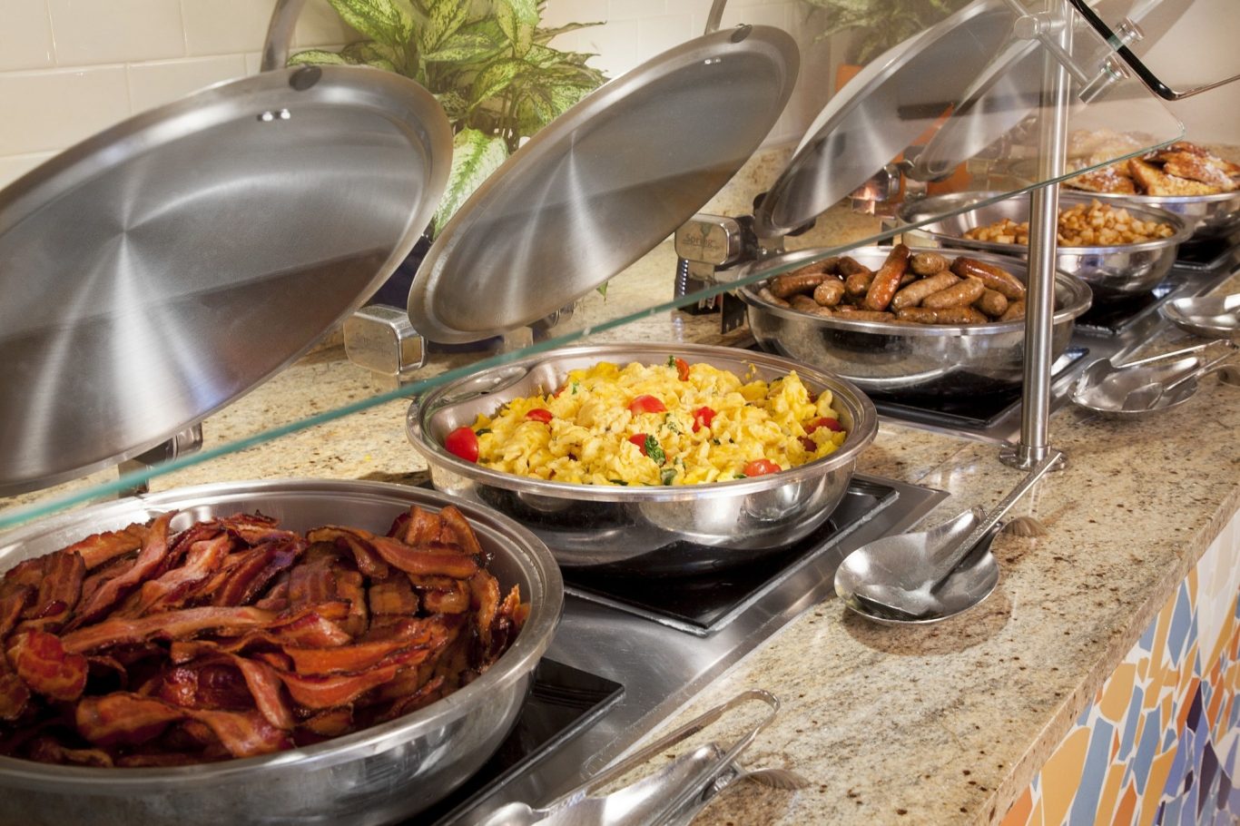 Buffet display featuring various dishes in metallic chafing dishes on a countertop.