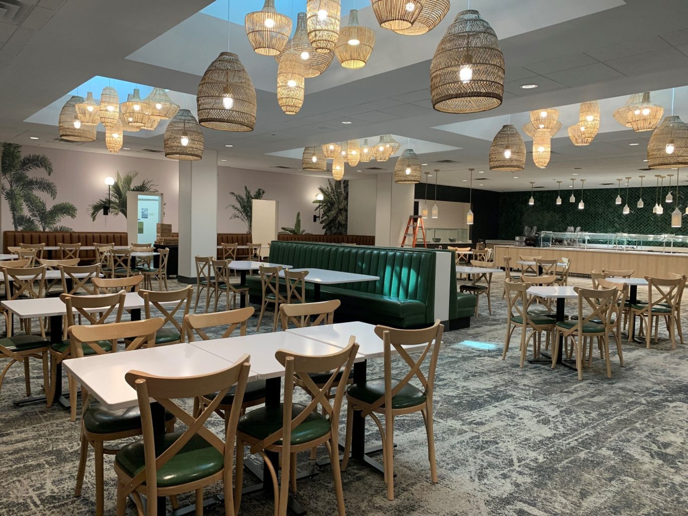 Modern dining area with wooden tables, green accents, and pendant lighting.