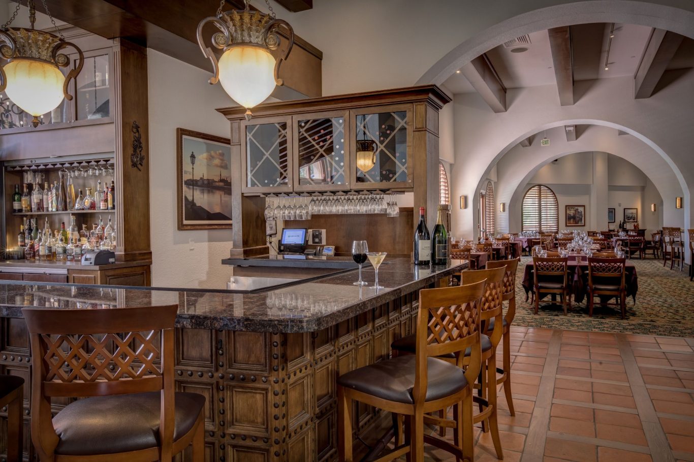 Elegant restaurant interior with a wooden bar, arches, and cosy seating arrangements.