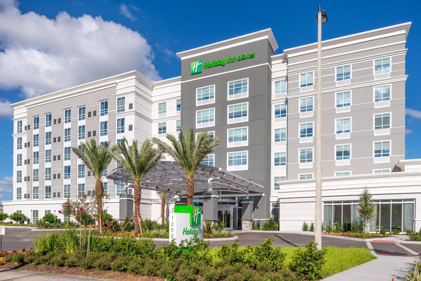 Modern hotel exterior with palm trees and clear blue skies.