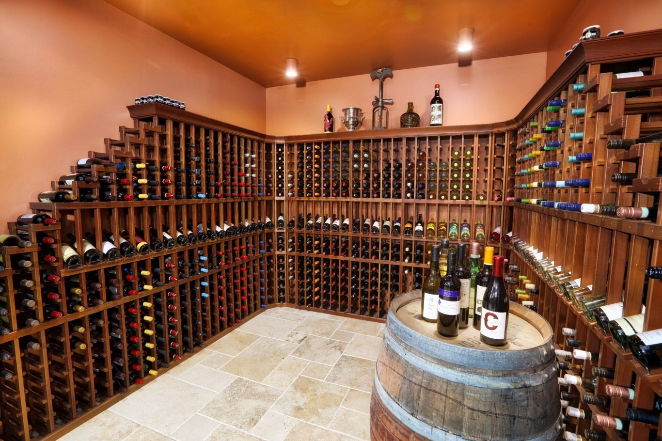 A wooden wine cellar with shelves full of bottles and a barrel displaying some wines.