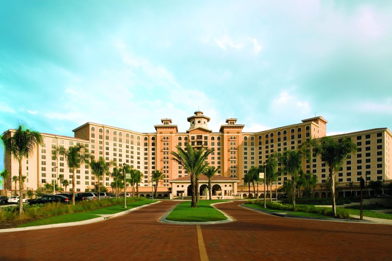 A large hotel building with palm trees and a blue sky.