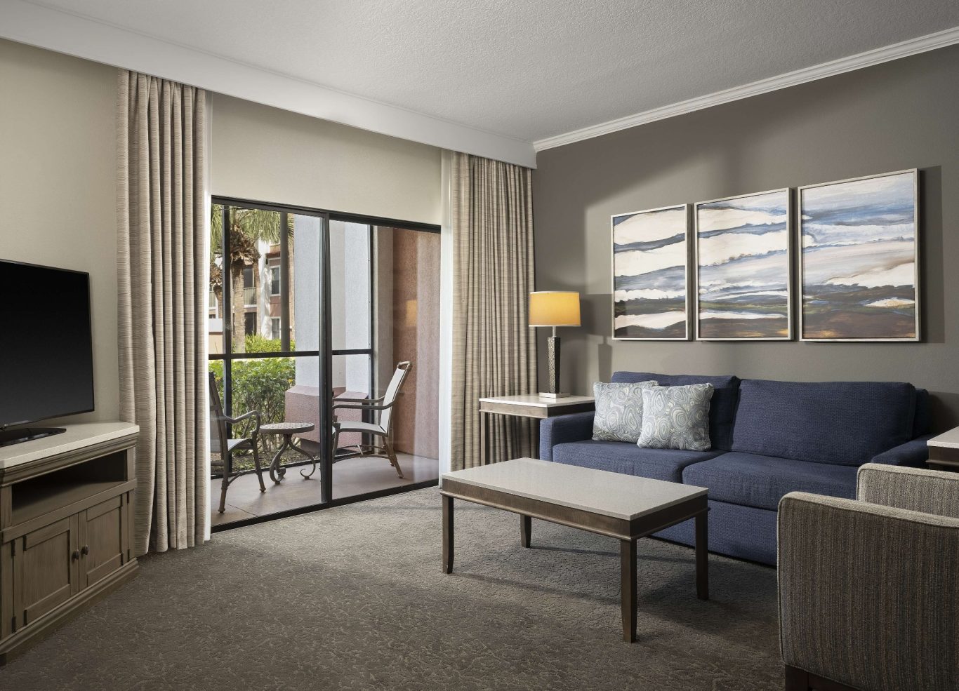 Modern hotel room featuring a sofa, TV, and balcony access with scenic views.