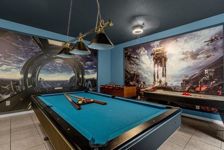 A pool table in a themed room with sci-fi mural and ceiling lights.