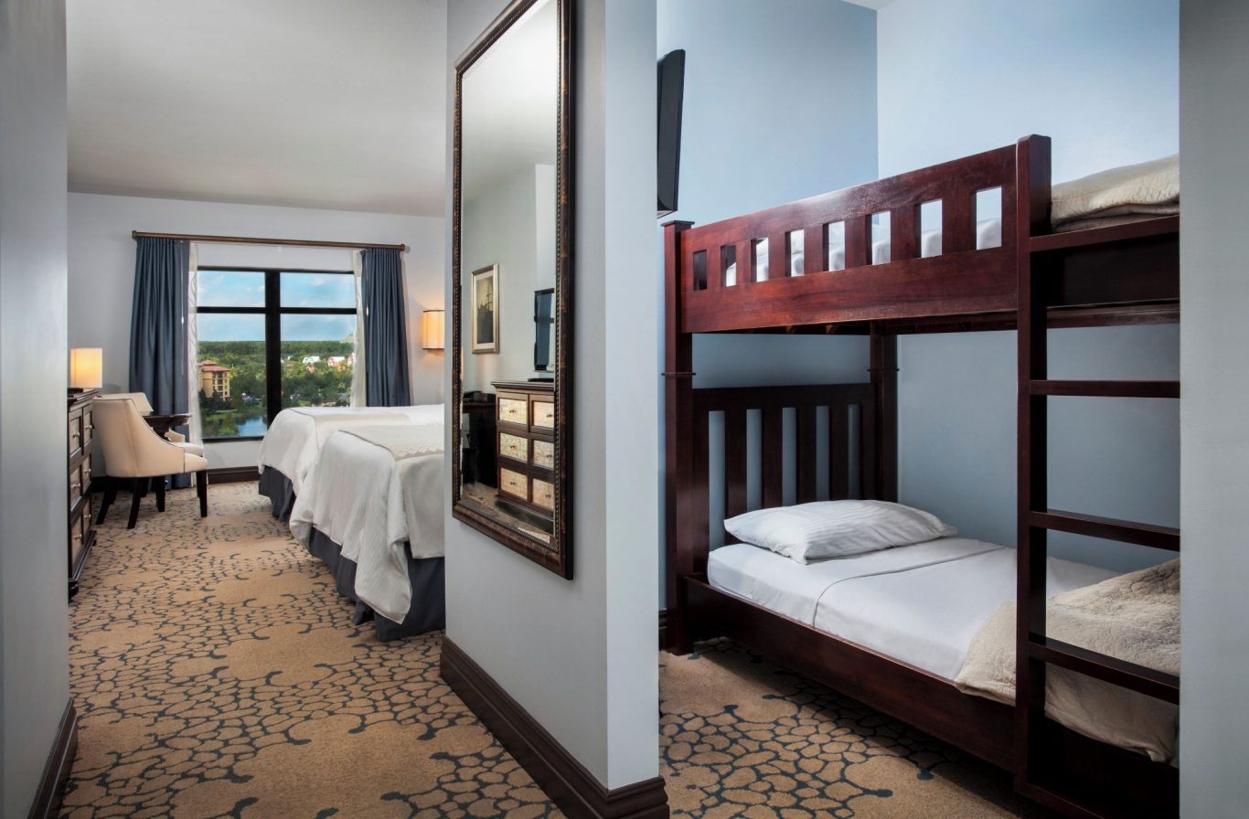 Guest room with a bunk bed, double bed, mirror, and large window looking outside.