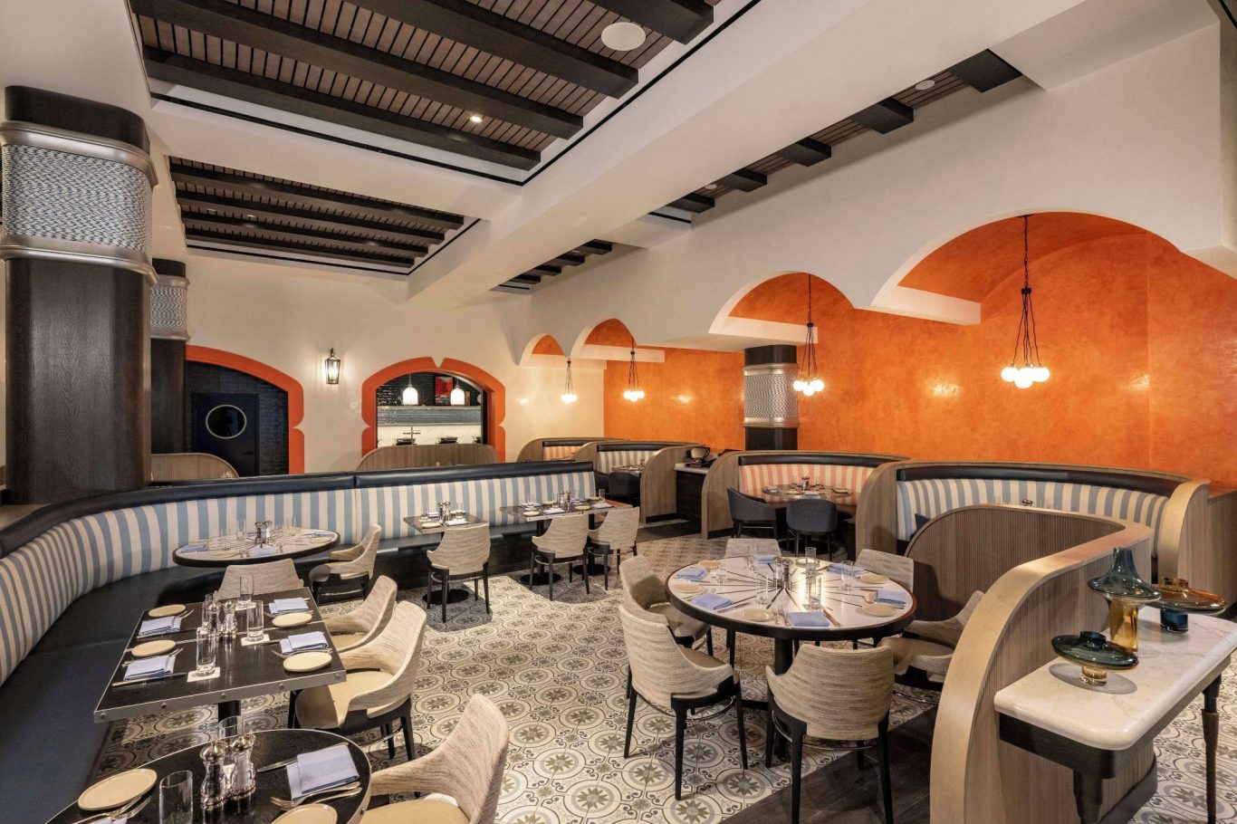 Stylish restaurant interior with curved booths and decorative walls in warm colours.