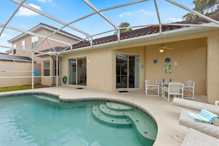 Backyard with a pool, loungers, and outdoor seating under a screened enclosure.