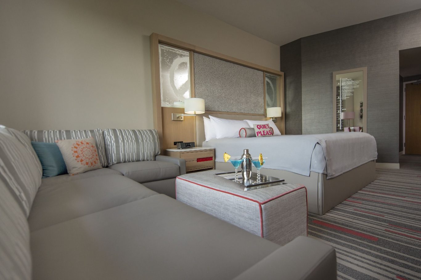 A modern hotel room featuring a bed, sofa, and coffee table with decorative items.