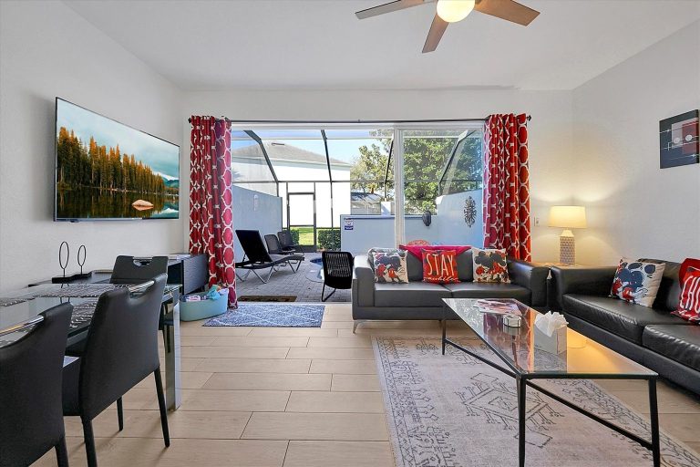 Modern living room with a glass sliding door, vibrant decor, and sleek furniture.