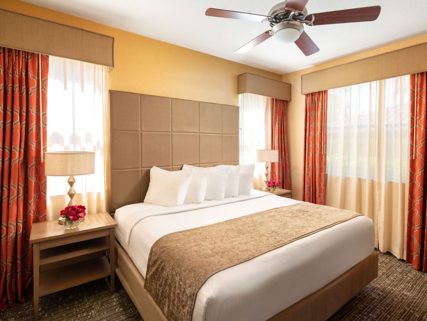 A bright, cozy bedroom featuring a large bed and warm, patterned curtains.