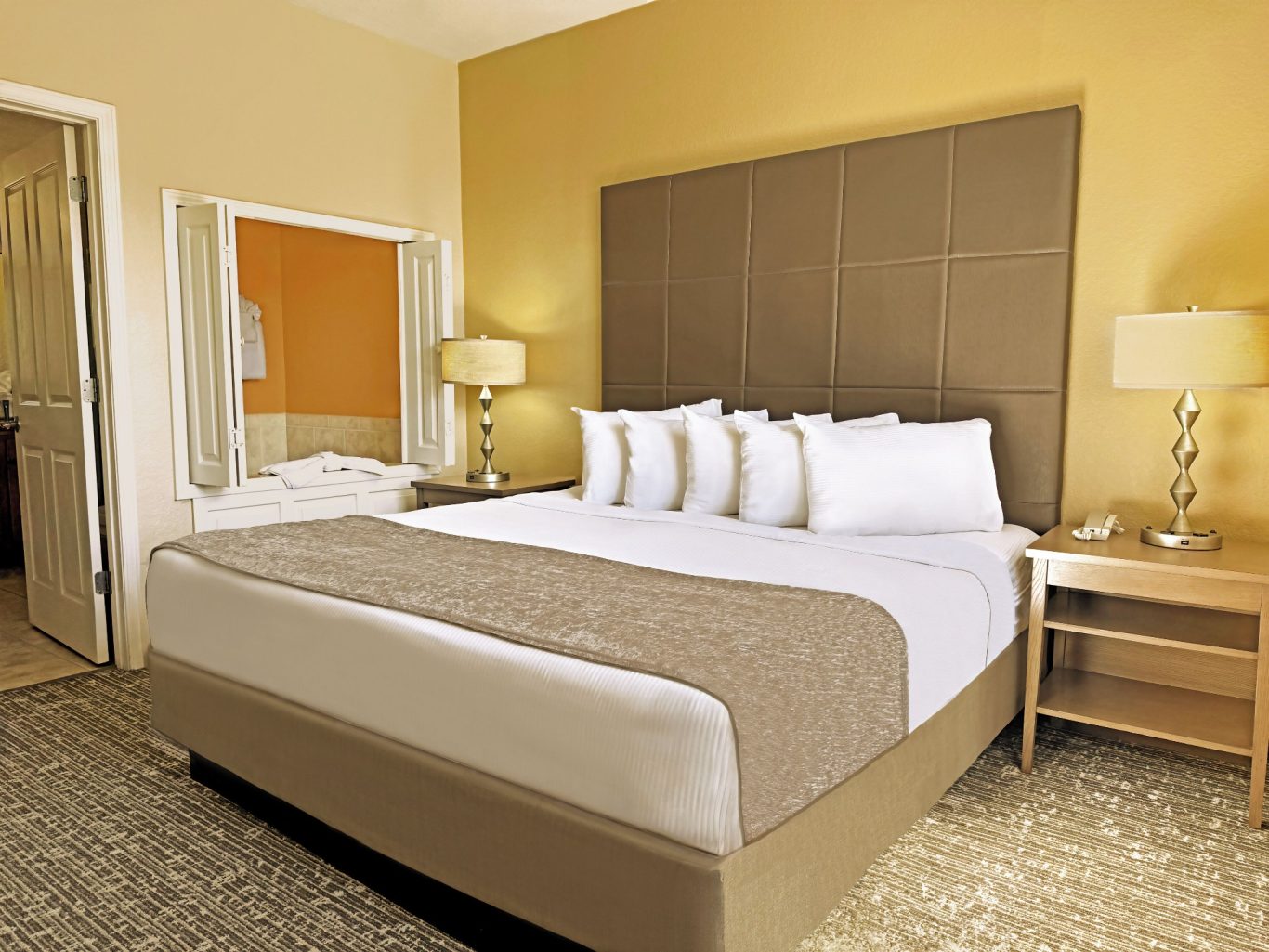 Modern hotel room featuring a king-sized bed and warm yellow walls.