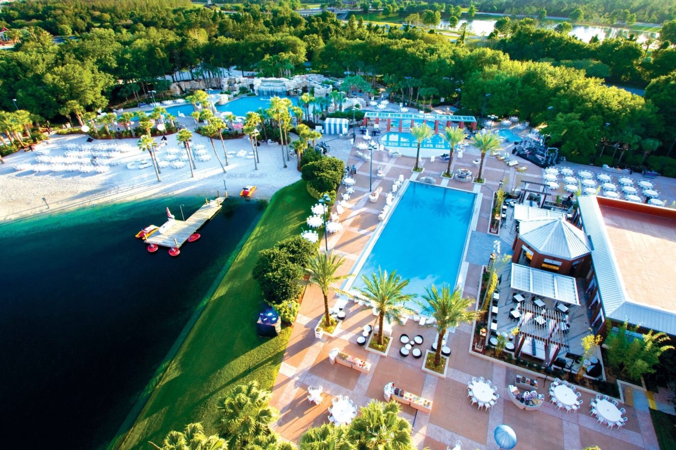 Aerial view of a resort with pools, sun loungers, and lush greenery.
