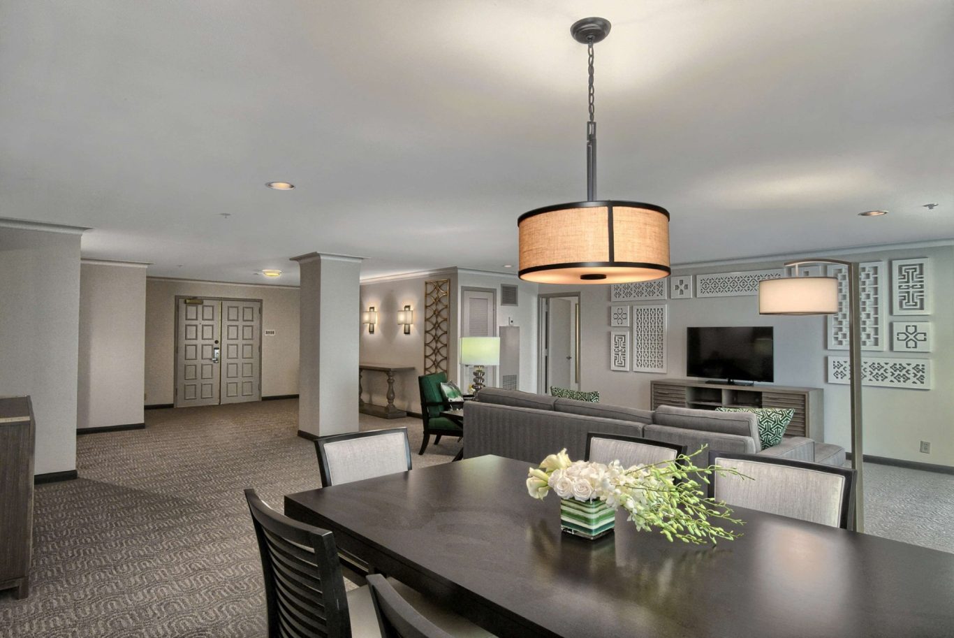 Modern dining area with a large table, stylish lights, and a comfortable living space.