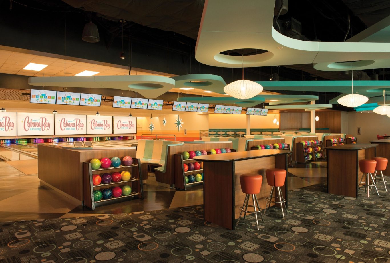 Modern bowling alley interior with colourful bowling balls and a bar area.