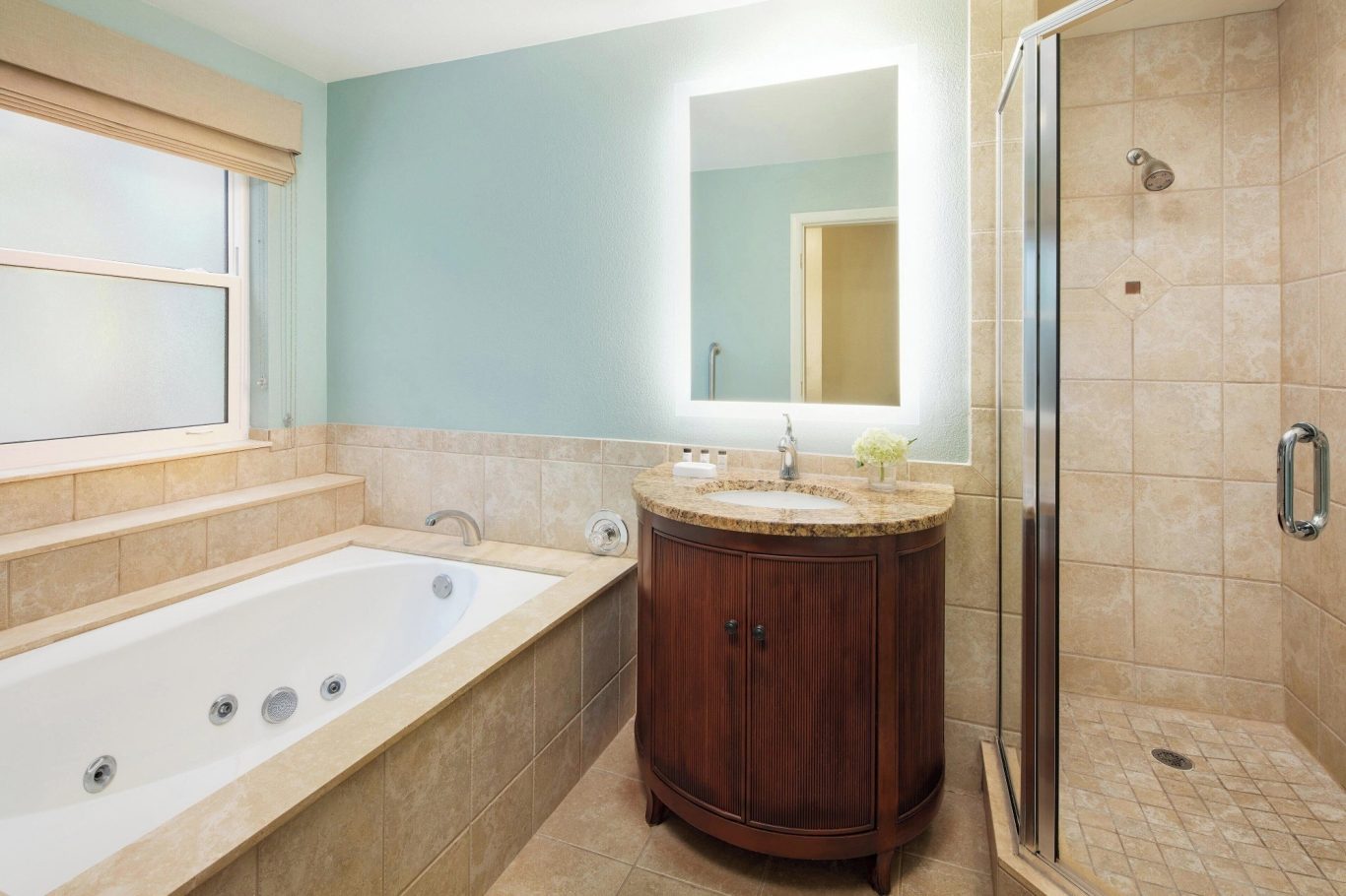 Modern bathroom featuring a bathtub, shower, and illuminated mirror.