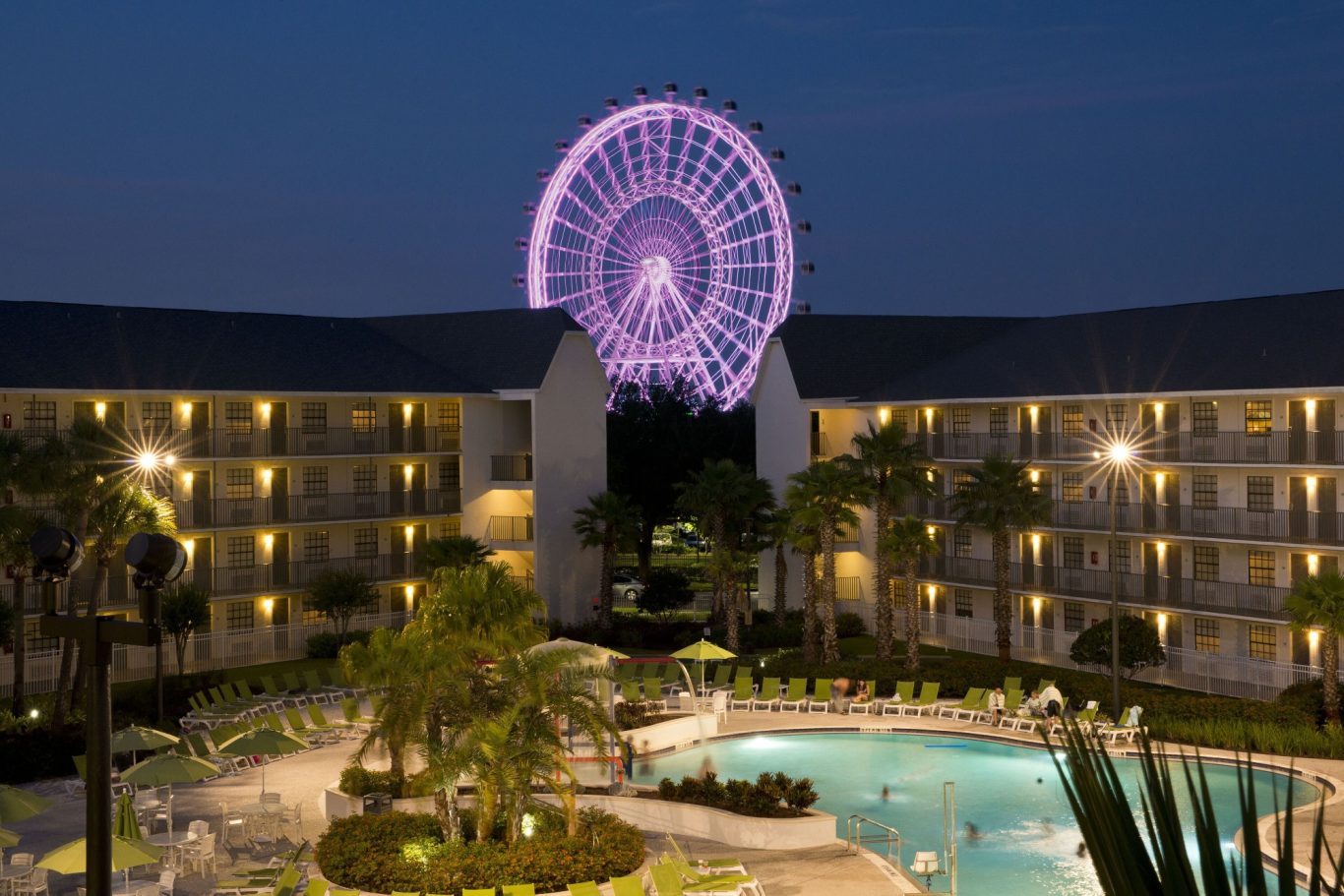 Resort pool area at night with a lit ferris wheel in the background.