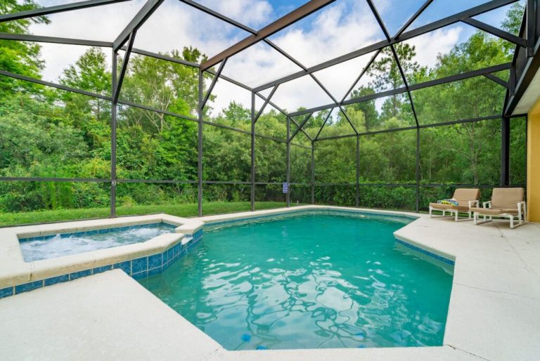 Private pool area with a hot tub, surrounded by greenery and a screened enclosure.