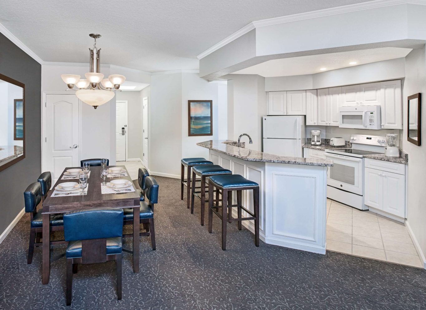 Modern kitchen and dining area with a table, chairs, and bar stools in a bright space.
