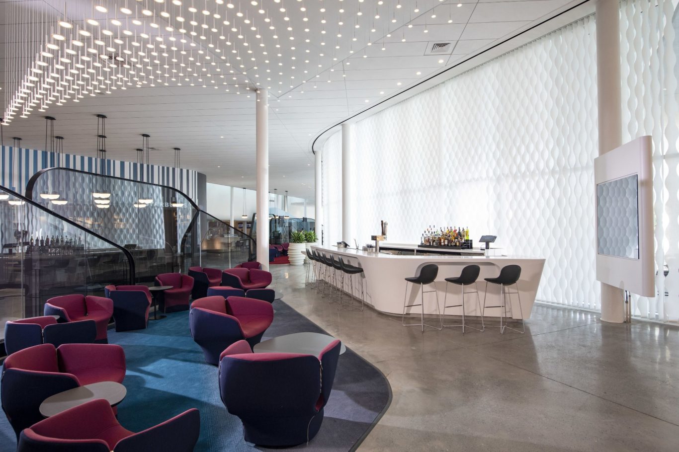 Modern reception area with curved seating, bright lighting, and a sleek front desk.