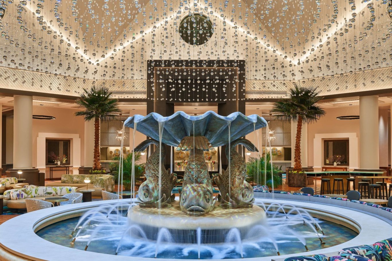 Grand hotel lobby featuring a central fountain, elegant decor, and palm trees.