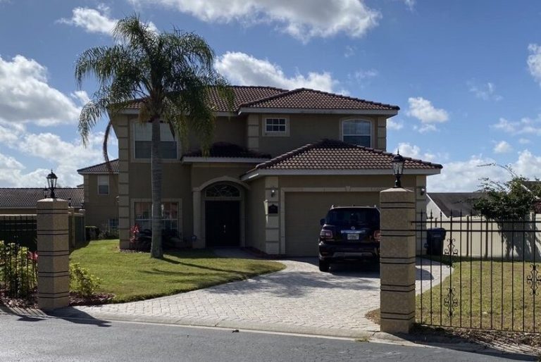 Two-storey suburban house with a palm tree and a black car in the driveway.