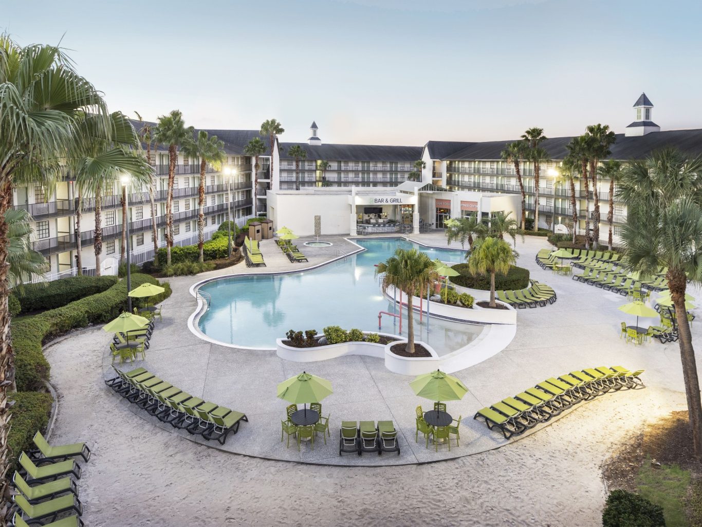 A modern hotel with a large pool and tropical landscaping.
