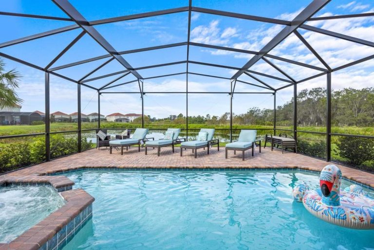 Outdoor pool area with sun loungers and a jacuzzi, surrounded by greenery and a blue sky.