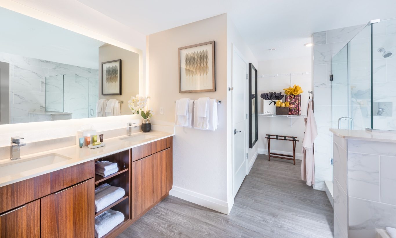 Modern bathroom with wooden cabinetry, large mirror, and glass shower.