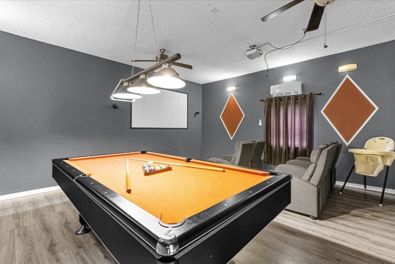 A vibrant billiard room featuring an orange pool table and modern decor.