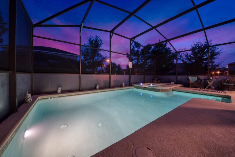 A serene swimming pool surrounded by a screened enclosure at twilight.
