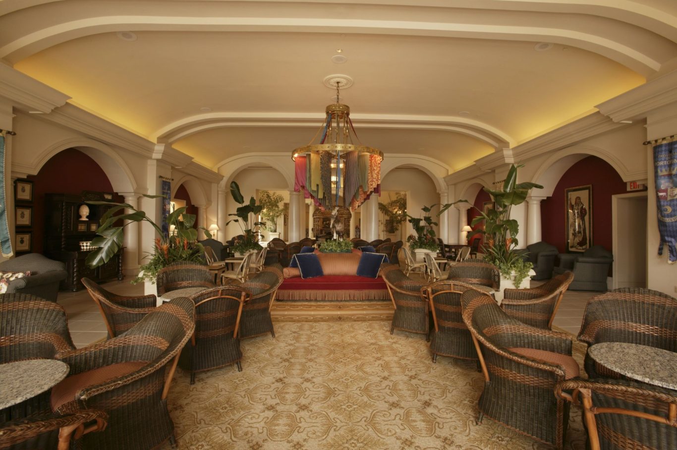 Elegant lounge with ornate furniture, plants, and a decorative chandelier.