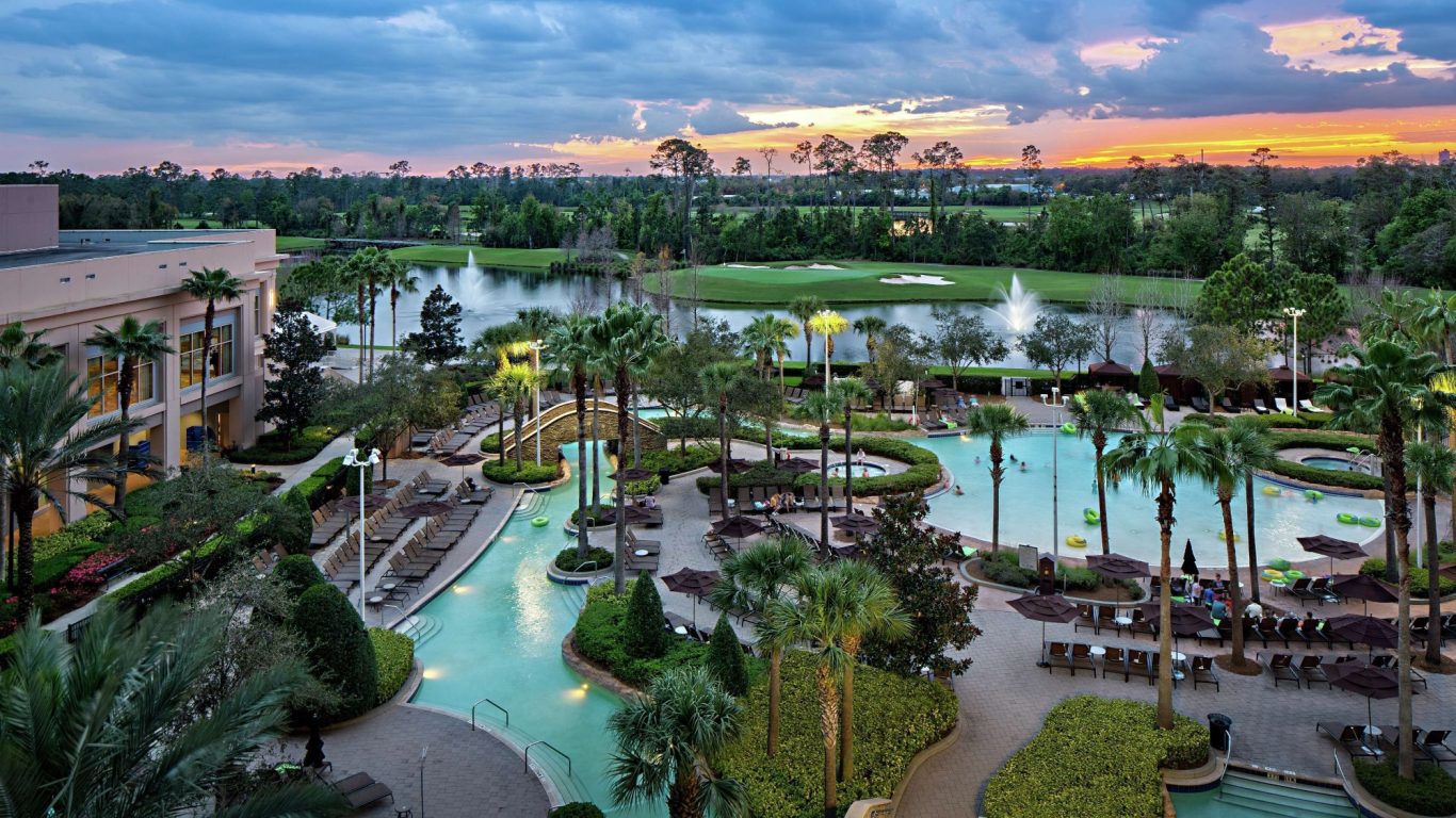 Resort with a pool and landscaped gardens, surrounded by palm trees at sunset.