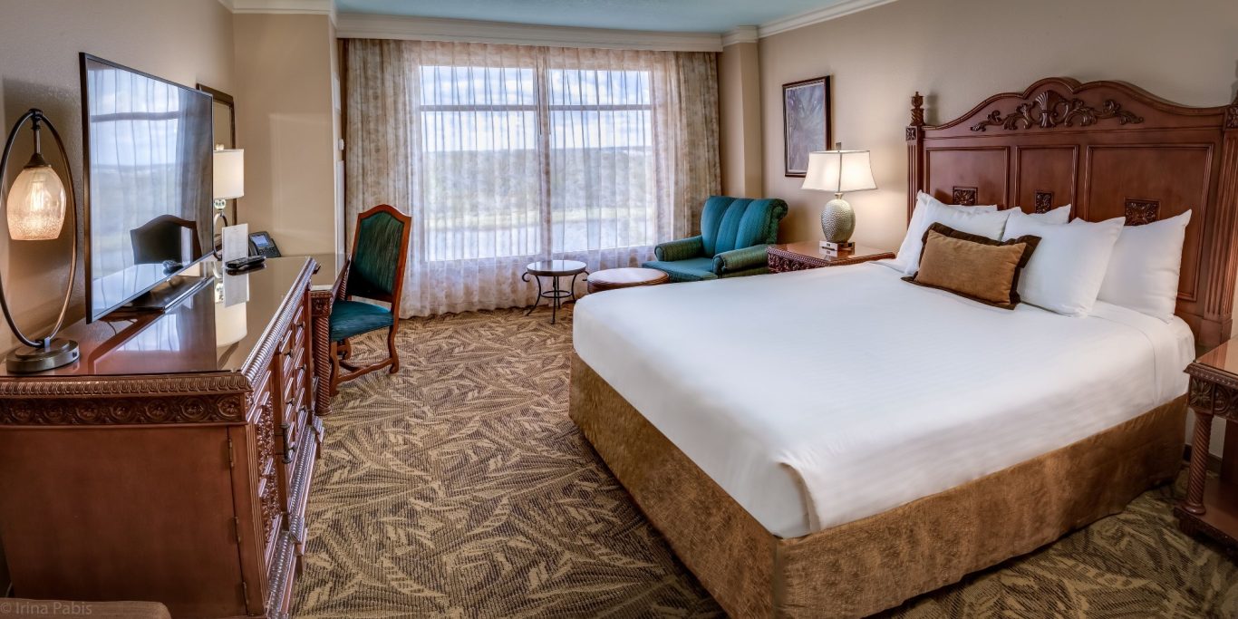 Hotel room featuring a king-size bed, seating area, and large windows with natural light.