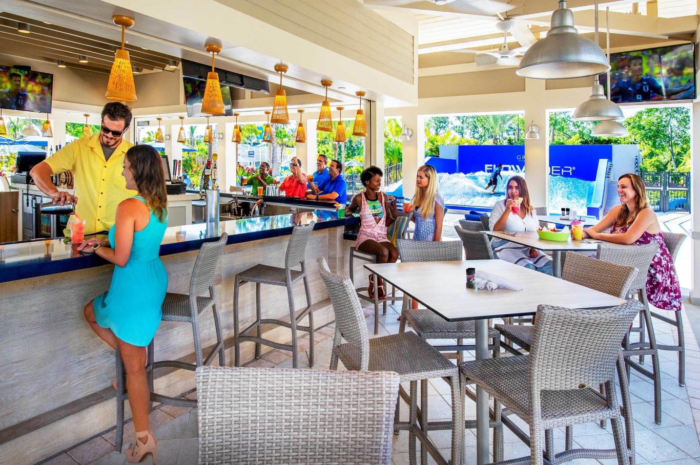 A lively bar scene with people socialising and enjoying drinks in a bright, modern setting.