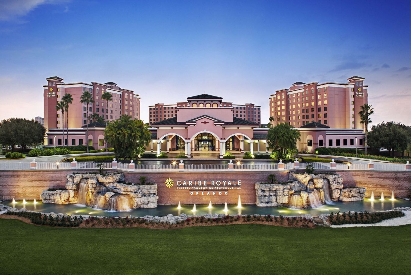 Luxurious hotel with palm trees, fountains, and a sunset backdrop.