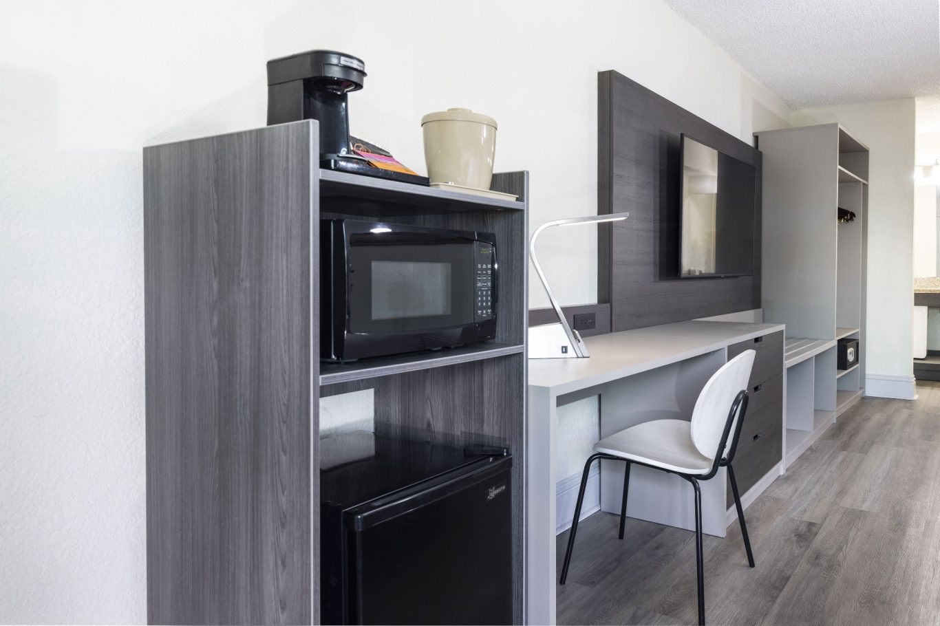 Modern kitchen area featuring a microwave, coffee maker, and a small fridge.